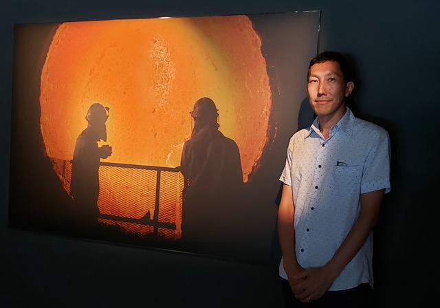 画像: 写真家の紀成道さん。今回のキービジュアルである作品に写る2人の技術者は、高度経済成長期から製鉄所と共に成長・発展をしてきた世代と、今、新たに経験を積み技術を継承するミレニアル世代。会場は、暗闇の中で溶けた鉄が浮かび上がり、生命体としての躍動感を真近で感じられる展示となり、とてもかっこいい。