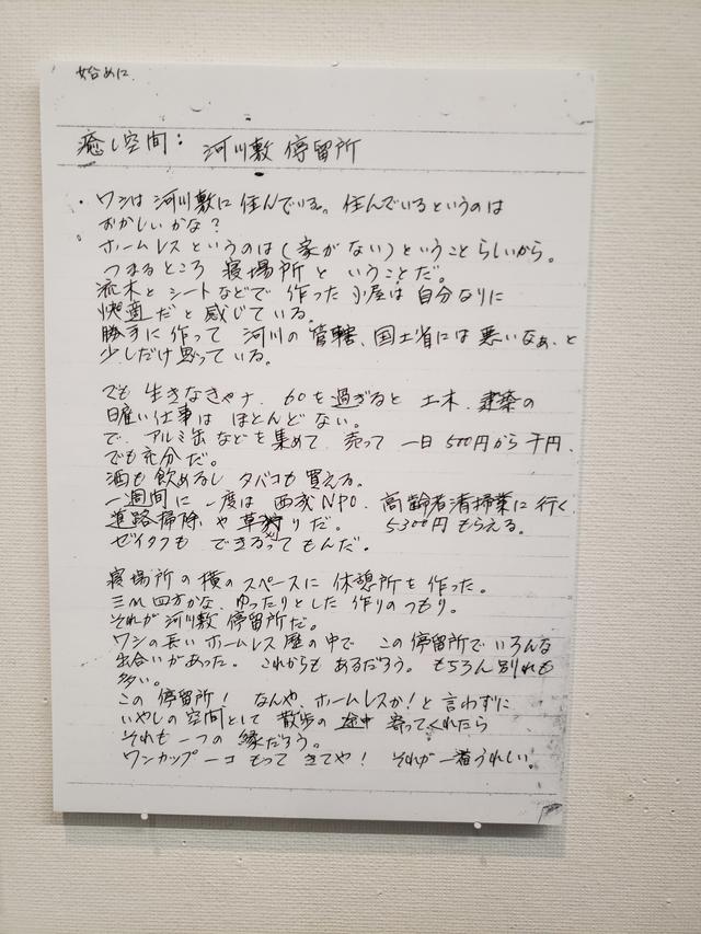 画像: 会場には、野口さんが撮影した河川敷に住む男性からの手紙も。 男性が河川敷停留所と呼ぶ空間のその背景には巨大な都心のビル群が立ち並びます。