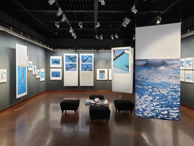 画像: 会場風景。「飛び込みは、屋外で風が吹いたり雨が降ったりする中でも行われたので、そういう浮遊感を出したいと思った時に、上から吊るして揺れる感じを出すようなこういう展示になりました」と村井さん。