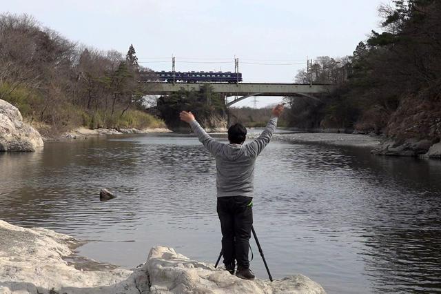 画像: 撮影後にはいつも感謝の気持ちを込めて列車に手を振る助川氏。 鉄道を愛してやまないのだ。
