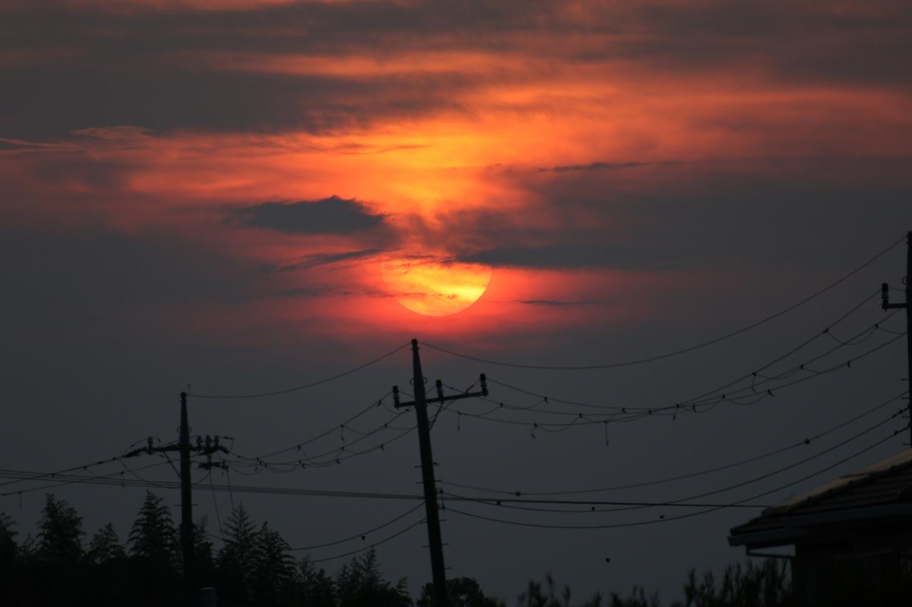 画像: 作例撮影のために撮り歩いていたが、この日の夕日はとてもきれいだった。480mm相当ならば太陽もそれなりのサイズで撮影できるし、手前に風景を入れれば圧縮効果も期待できる。標準ズームだけでは撮れないカットだ。こういうときは高倍率ズームのありがたさをしっかり感じられる。 ■絞りF6.3 1/640秒 マイナス0.3露出補正 ISO200(300mm時)