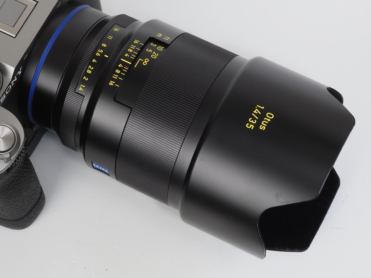 画像: 専用の花型のフードを装着してみます。たしかに効果的ですが長くなります。でも、強力なT*コーティングが施されているのだからなくても問題はないはず。あ、筆者はフードを使用した方がレンズの保護の面なども考えて良いことかと思っています。