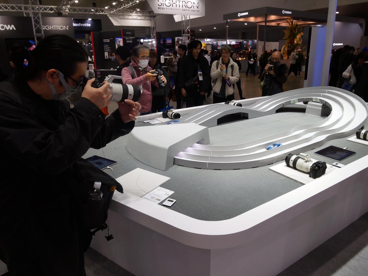 画像: コレ、編集部・モリタも試したのですが、そもそも高速で走るミニ四駆をフレーミングするのが大変で、ヤナ汗をかきました。でも、まれに上手くフレーミングすると瞬時にAFが食い付く!というスゴさが味わえました。技術の進化を体験させることで商品力をアピールするとは、こういうコトなのでしょうねぇ。