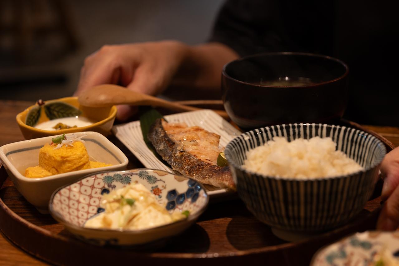 画像: 撮影からの明くる朝、食卓の一枚をF5に絞って撮影。最短撮影距離84cmと、決して寄れるレンズではないものの、この距離感でも焼き魚の皮目の焦げ目や繊維からにじんだ脂までしっかり解像しており、実直な描写力の一端がうかがえる。 ■絞りF5 1/60秒 ISO1000