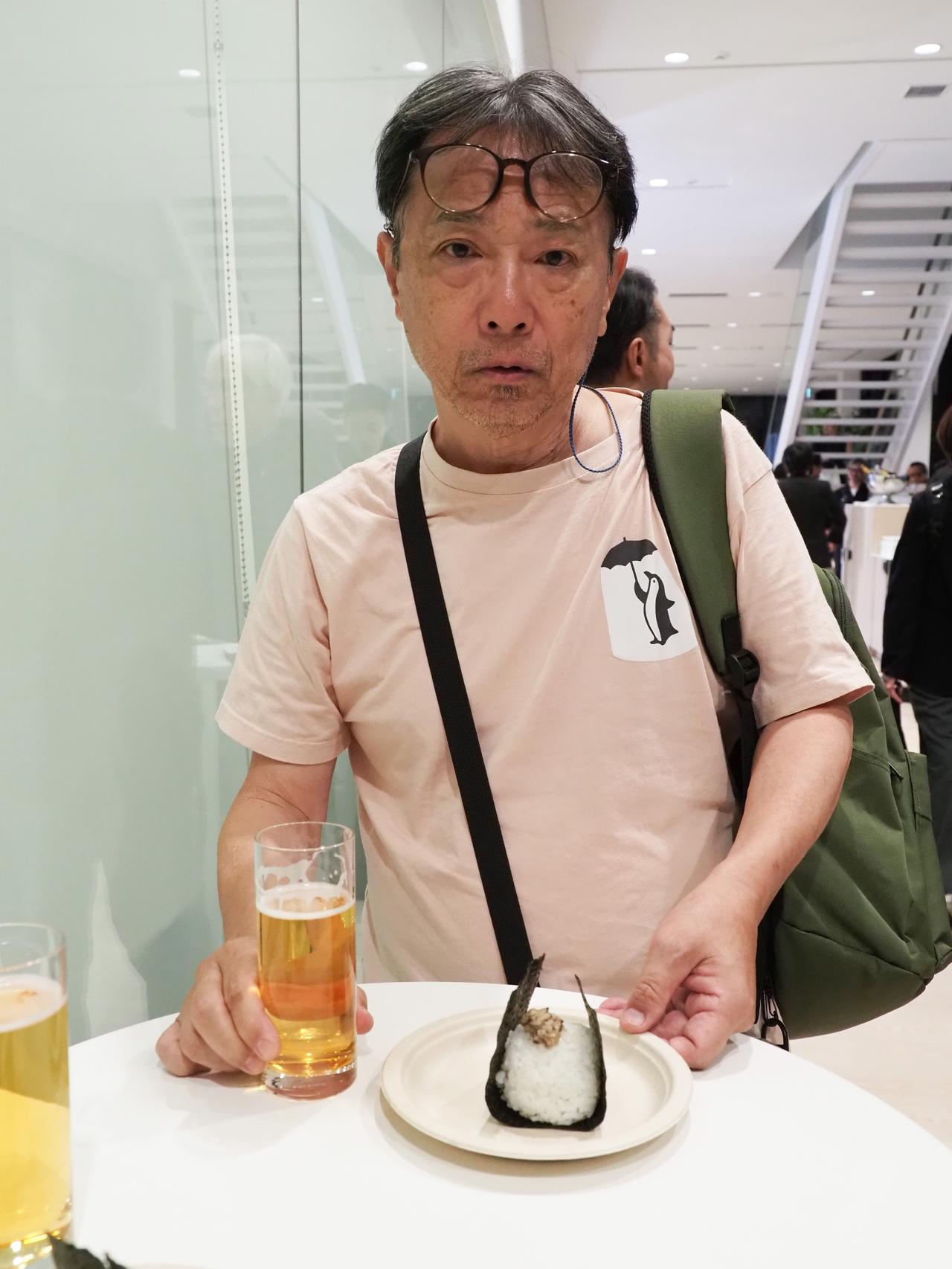 画像: ビール片手におにぎりを食すマロニエ。