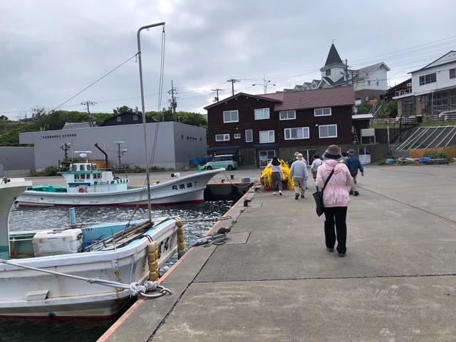 画像: 宿到着後、希望者は地元ガイドの方の案内で、1時間街歩きを行いました。 昔の写真を見ながら、今と比べて見たり、港ではナマコ漁の説明を受けたり♪