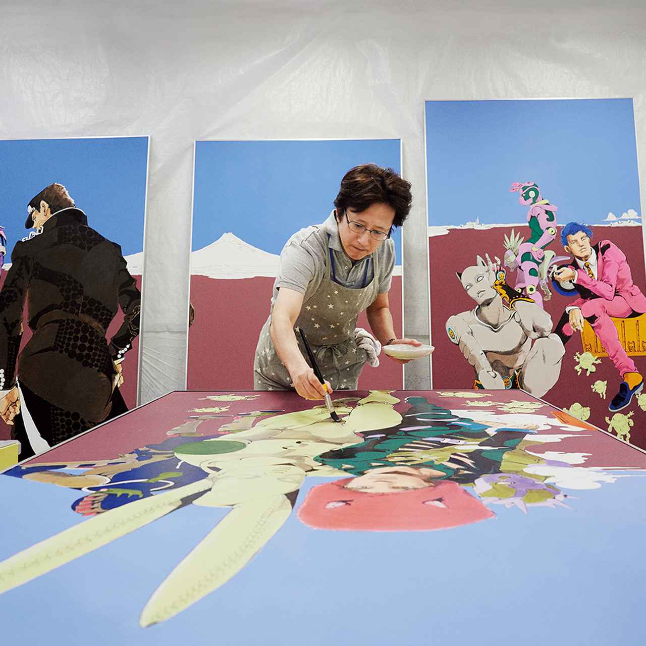 画像: 12枚の大型原画を仕上げる荒木。 モチーフは『ジョジョの奇妙な冒険』のキャラクターだ。「等身大だと、顔や体をなでるように筆が動く。すると何千回も描いてきたキャラクターが、いっそう愛おしく感じられるんです」 ほかの写真をみる