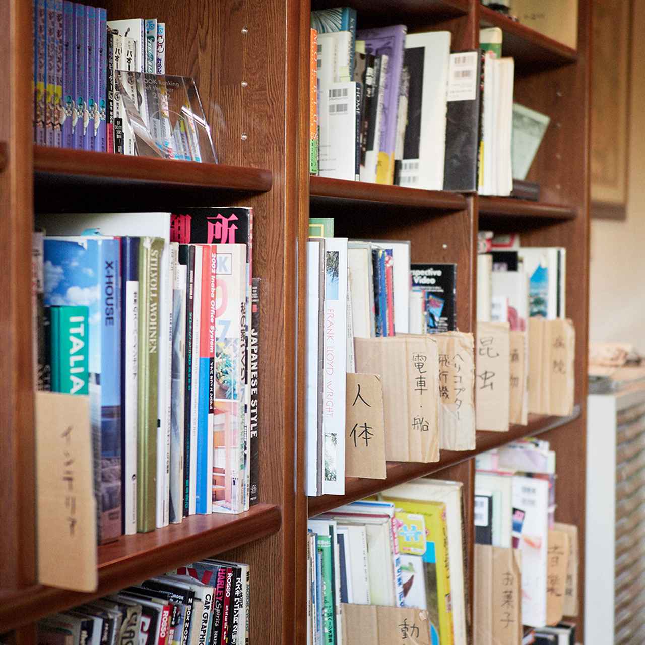 画像: アトリエの本棚には、世界各地の建築やインテリア、乗り物などの参考資料が並ぶ。なかには料理のマナー本もあり、徹底したリアリティを求める荒木のこだわりがうかがえる ほかの写真をみる