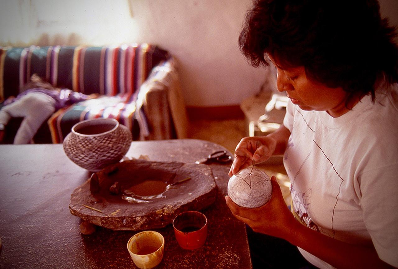 画像: 土器の絵付け。フリーハンドで自然のモチーフを描いてゆく