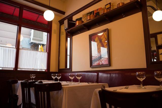 画像: 店内は、フランスのビストロそのもの。ボルドー色のベンチシート、白いカフェカーテン、背の低いワイングラス……。本場そのものの雰囲気を醸し出す。お客様に外国人ファミリーもよく見かける