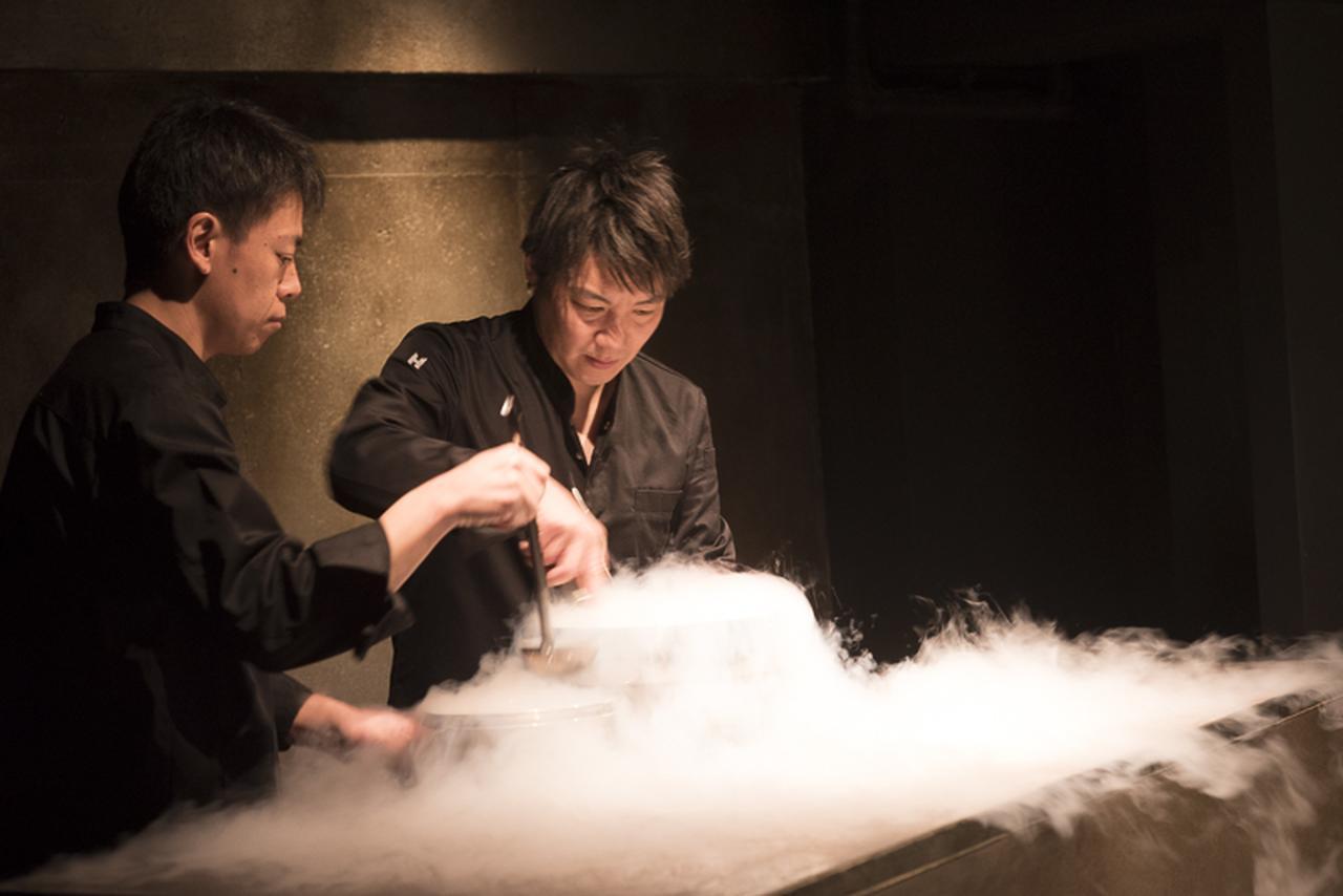 画像: ステージのようなキッチンで、液体窒素を使ってアイスクリームを作る薮中章禎シェフ（右）。石川県は能登の出身。能登直送の魚介類を使う
