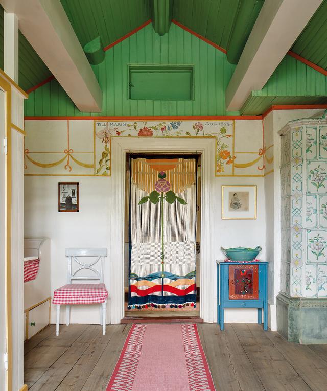 画像: スンドボーン村にある画家カール・ラーションと妻カーリンの家には14の部屋がある。カーリンは、1909年に羊毛と漁網糸で編んだマクラメのタペストリー『The Rose of Love』(愛のバラ)を制作し、寝室の入り口に飾った。その上にある花の絵は、1894年のカーリンの「名前の日」(註:スウェーデンのカレンダーは日付の横に名前が記されており、誕生日のほかに名前の日を祝う習慣がある)を記念してカールが描いたもの。