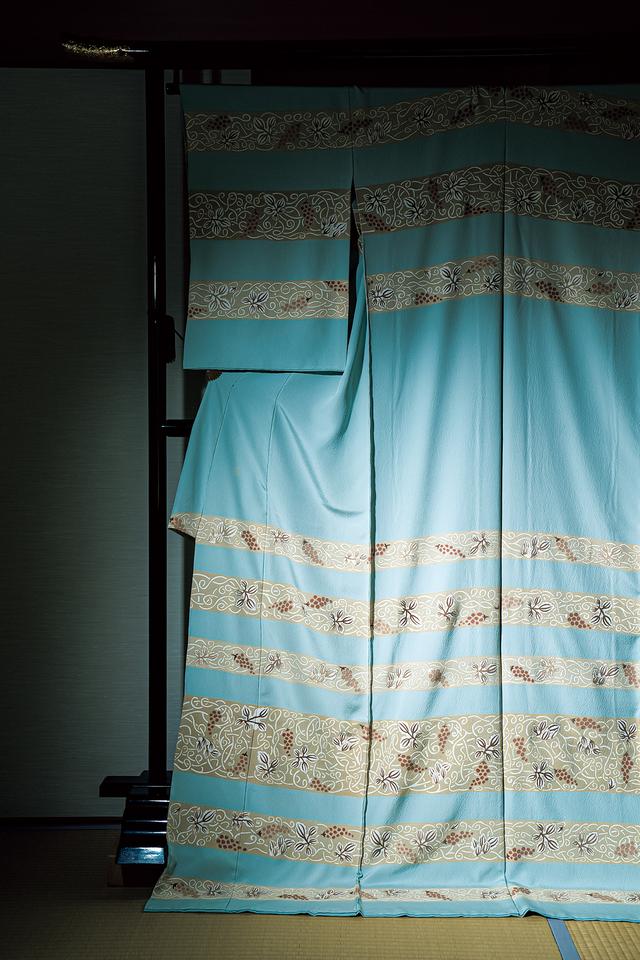 画像: ミラノの寺院の壁画から想起した、小倉隆の作による訪問着「壁画 葡萄唐草」。ランダムな幅の横段に濃淡の丁子色を配し、流麗な葡萄唐草を糊の＂白あげ＂を効かせて表現した。透明感を保ちながらも、冷たい印象にならないように、ニュアンスを帯びた水色にこだわる。