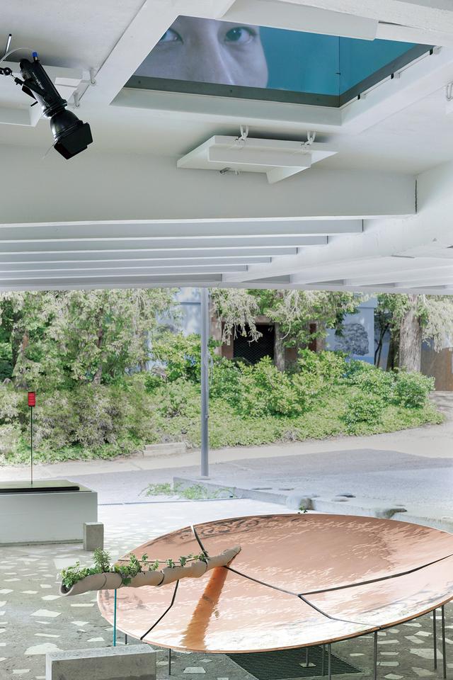 画像: SUNAK（I 木内俊克＋砂山太一）が手がけた1 階の半屋外空間では、フロアをつなぐ〈穴〉が担う意義や、日本館全体を巡る〈動線リング〉との関係性を抽出した。2 階で展開する〈穴〉の発話に連動して明滅する光を反射する銅板のオブジェや、動線を断片的にトレースする植物のポットなどにより、これらの建築的要素を可視化している。