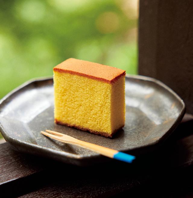 画像: 1624年創業。2024年に400周年を迎えた「福砂屋」のカステラは、卵も白身と黄身に分け、白身を十分に泡立ててから他の材料を加える「別立法」を採用。手間を惜しまないこだわりの製法で焼き上げる。黄金色の生地はふんわり、しっとりした味わいは底の双目糖のシャリッとした口あたりとあいまってまさに風味絶景、眼福口福。「カステラ小切れ0.6号」1 本¥1,458/福砂屋 TEL.095-845-2938