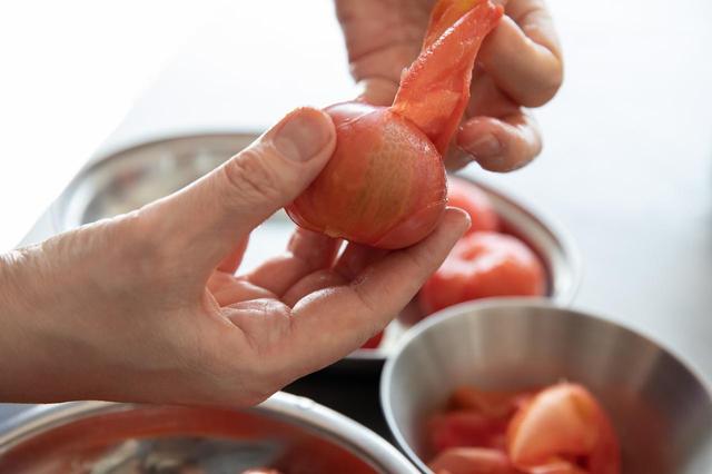 画像: 鍋に昆布水を作っておく。トマトの湯むきをする。鍋にたっぷりのお湯を沸かし、トマトを入れ、3〜4秒で引き揚げ、皮をむく。皮は取り置く。