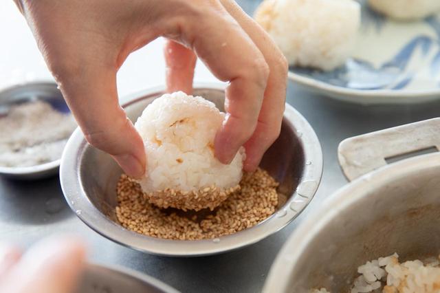 画像: 米2種類は合わせて研ぎ、同分量の水を加えて1時間くらいおく。炊飯器かまたは鍋で炊いておく（鍋の場合は沸騰したら弱火で15分ほど炊いて蒸らす）。ご飯が炊けたら、手に塩をつけ、丸くむすび、炒りごまをつけて盛り合わせる。
