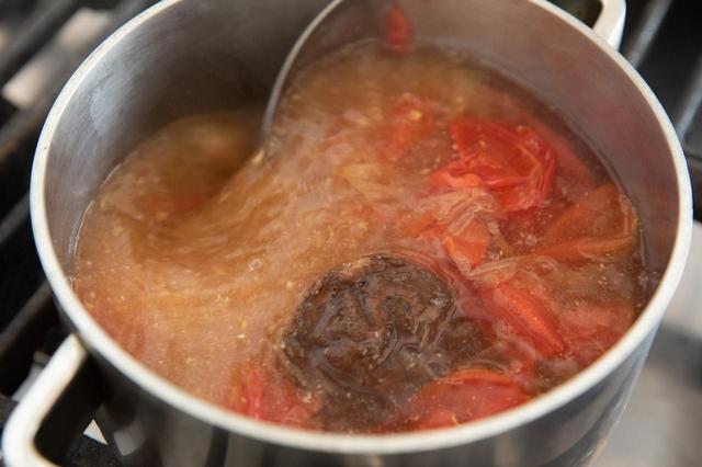 画像: 昆布水の鍋に、戻し汁ごと干し椎茸を加え、弱火にかける。煮立ってきたら鰹節を加え、味噌を溶かし入れる。トマトの皮も加え、弱火で2分ほど煮て火を止める。