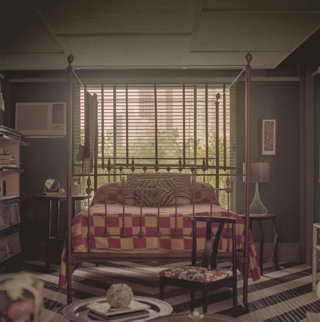 画像: 三姉妹のおそろいの寝室のひとつには、20世紀初頭のアメリカ製の真鍮と鉄でできたベッドが置かれている。その上にはフィリピン北部のイロコス地方の伝統的な手織り工法によって織られたイナベルと呼ばれる綿布でできたカバーがかかっている。ベッドの前にあるのは、ビニール張りの座面に柄がほどこされたヴィンテージの日本製のチェア。