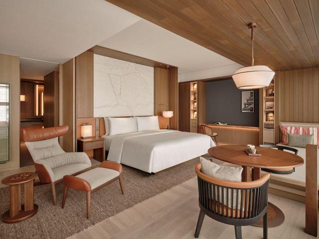 画像: こちらはデラックススイート。客室は落ち着いた木目調が特徴。ベッドボードには日本らしさを感じる和紙のアートが。部屋の写真右側は畳のスペースになっている