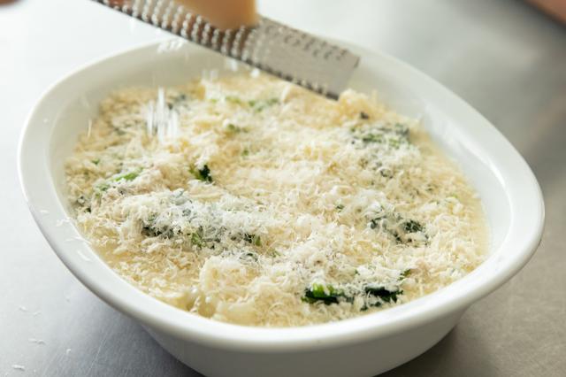 画像: 耐熱容器に薄くオリーブオイルを塗り(分量外)、鍋の中身を移す。その上にほうれん草をのせ、チーズを全面にすりおろし、パン粉をたっぷり振る。