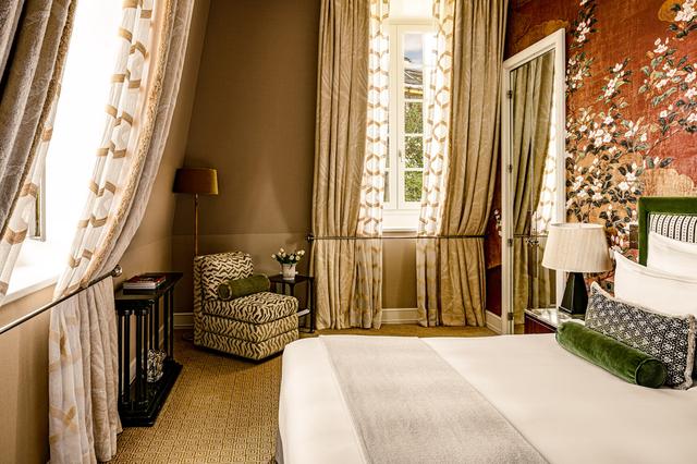 画像: 赤を基調にしたデラックスルーム。壁の傾斜を利用してバーを取り付け、カーテンのタッセルの役割をしている