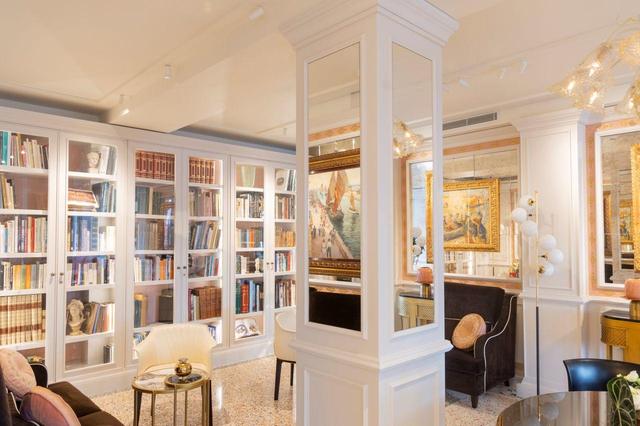 画像: レセプションの横にあるサロンはゲストが自由に寛ぐスペース。ザ・プレイス・オブ・ワンダーズに携わるアーティストたちの作品を展示することも。書棚にはバビーニ家が所有する書籍が並ぶ PHOTOGRAPHS: COURTESY OF LONDRA PALACE VENEZIA