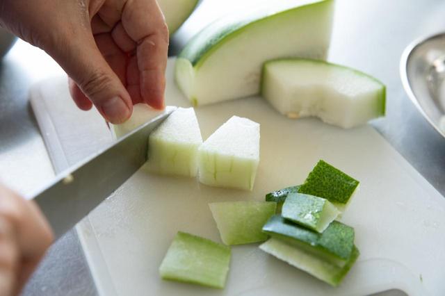 画像: 鍋に800mlの水と昆布を入れて、20分ほどおいておく。冬瓜は縦に2等分し、横に3cm幅に切り分け、種とワタを切り取る。皮を包丁でそぎ、ひと切れを3等分に切り分けると、ひと口大の扇形になる。