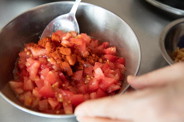 画像: トマトをボウルに入れて塩を軽く振り、オリーブオイルを小さじ１、パプリカパウダーも加えて混ぜ合わせ、冷蔵庫で冷やしておく。