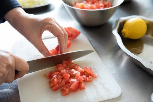 画像: 鍋にたっぷりお湯を沸かし、トマトを入れる。4〜5秒経ったら引き上げて、手早く皮をむく。2等分して芯を取り、角切りにする。切る際に出るトマトの水分もボウルに入れる。
