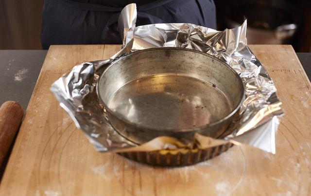 画像: 7 フォークでピケし、アルミホイルをのせ、その上にひと周り小さいケーキ型をのせる。タルト用の重石があれば、ケーキ型の代わりに重石をのせる。210～220℃に温めたオーブンで10〜15分ほど、生地の周りが少し色つくくらいに焼き、取り出す。