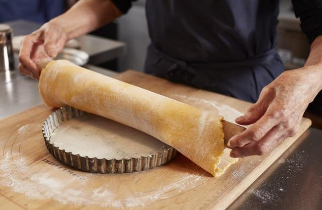 画像: ４ 生地をめん棒に巻き取ってタルト型の上に広げる。