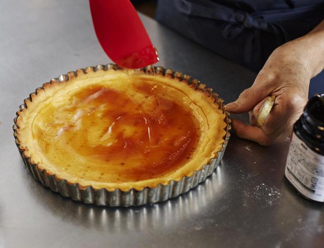 画像: 8 7の生地の粗熱が取れたら、アルミホイルとケーキ型をはずす。はちみつ2種類をたっぷり塗り、さらに210~220℃のオーブンで約15分焼く。様子を見ながら、生地がカリッと狐色に美味しそうに色づいたらオーブンから取り出し、常温になるまで置いておく。