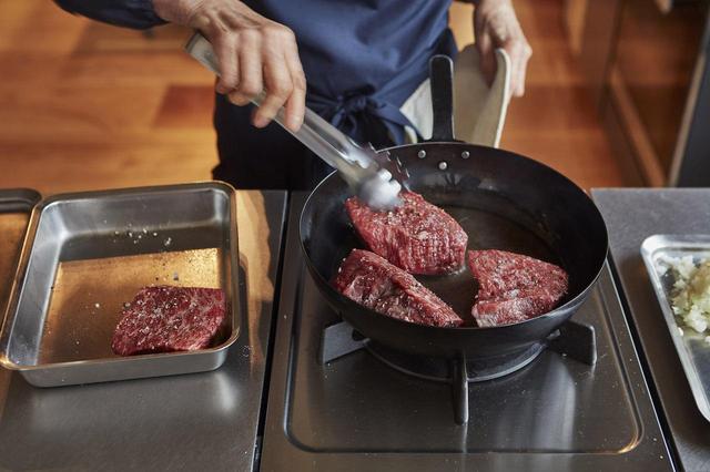 画像: １ 牛肉を4等分にし、軽く塩、胡椒する。煮込み用の深鍋を横に置いておく。フライパンを熱し、オリーブオイルを入れ、肉を入れて全体に焼き目が付いたら、深鍋に入れていく。