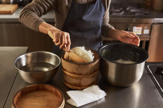 画像: 3 ごはんが炊き上がったら5分ほど蒸らす。しゃもじを水につけて、釜からそっとごはんをすくい、おひつに移す。ごはんを移すたびにしゃもじを水につける。ごはんを決して混ぜないこと、おひつに移す段階でごはんをひっくり返すのがコツ。全部移したら、しゃもじでそっとごはんを切る。