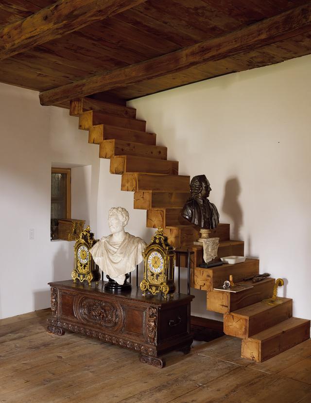 画像: 階段に置かれた1790年製のブロンズ胸像。16世紀の彫刻家アレッサンドロ・ヴィットリアによる石膏胸像の両脇に、アンティークのフランス製マントルクロックが対をなして置かれている。