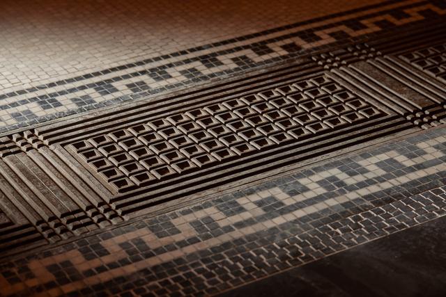 画像: 廊下のモザイクタイル。この模様はのちに英国軍の手榴弾のケースにも取り入れられた。鋳鉄製の格子がはめ込まれているのはイギリス初の電話回線が敷かれていた名残り