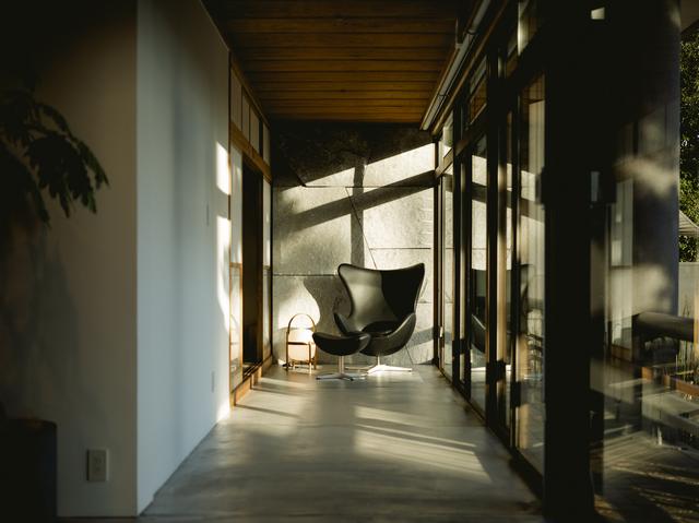 画像: 庭を望む1階の廊下にはフリッツ・ハンセンのエッグチェアが静かに佇む COURTESY OF ANABUKI-TEI