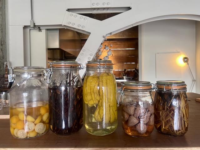 画像: ワインのほか、フルーツやハーブを漬け込んだ焼酎もズラリ。クロモジを漬けたイイチコをローズヒップティーで割ると赤ワインのガメイを彷彿させる味になるそう