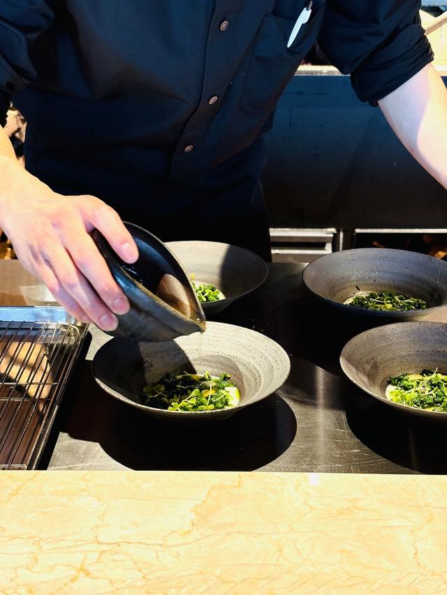 画像: 薪火と料理の焼きあがりや仕上げの様子も楽しめるカウンター席にて。石浜綾シェフがこだわっているフラン、茶碗蒸し。ながみねファームの卵、鯛の骨からとった出汁と親鳥の出汁、わさび菜、春菊、ハーブ