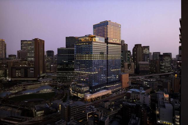 画像: JR大阪駅に隣接する複合施設「グラングリーン大阪」南館。高層階に位置する「ウォルドーフ・アストリア大阪」。手前の建物、最上階のガラス張り部分が２フロア吹き抜けの「ピーコック・アレー（Peacock Alley）」。客室は奥の建物31階から38階部分を占め、252室のすべての客室から大阪の眺望を望むことができる