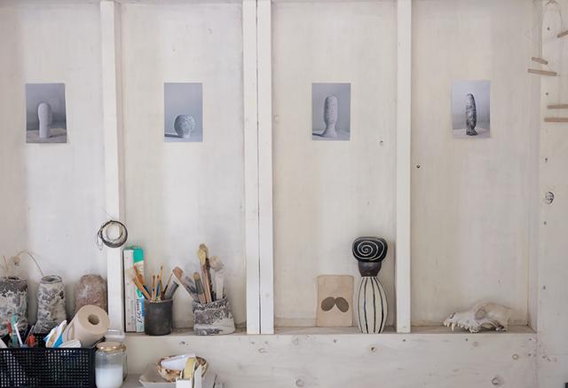 画像: アトリエの壁に貼ってあるのは、前回の個展で発表した作品。写真も自身で撮影する。その下、右端の動物のスカルの左隣に置かれているのは、小前の過去の作品。