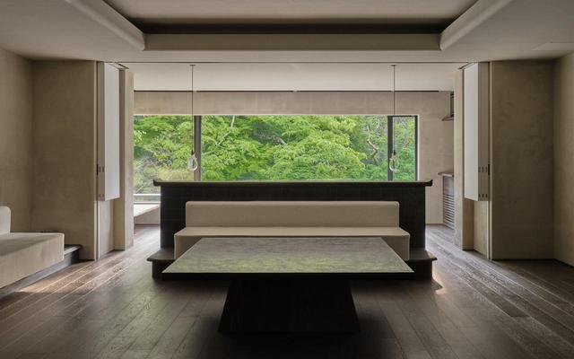 画像: 「夏の５」のリビングルーム。中央のテーブルは金沢の漆作家・杉田明彦氏がこの部屋のために制作。窓の手前に置かれたベッドから鶴仙渓の景観を独占できる