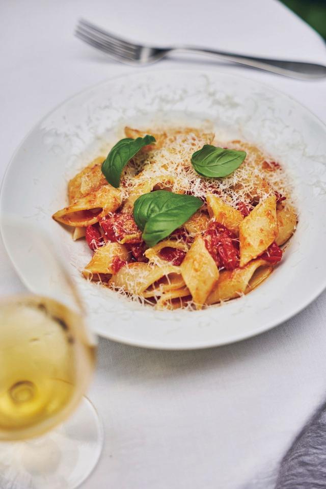 画像: イタリアでの暮らしから生まれたメニューも多い。フレッシュなミニトマトで作るトマトソースのパスタ。トマトのうまみは皮のすぐ下にあるので、皮をたっぷり使えるミニトマトを用いるとおいしい。ミニトマト2〜3パックはへたを取り、横半分に切る。鍋にオリーブオイルとつぶしたにんにくを入れ、香りが立ったらトマトを入れ、蓋をして煮込む。煮崩れてきたら軽くつぶして煮詰める。全体にとろりとしたら塩で味を調え、ゆでたパスタにからめて器に盛る。パルミジャーノ・レッジャーノをすりおろし、バジルをのせる。