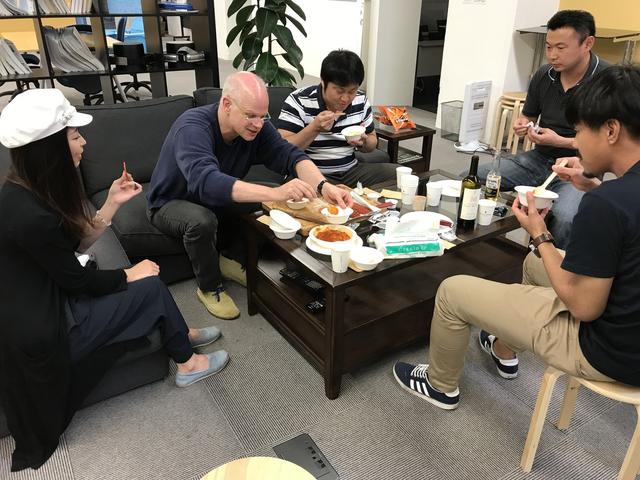 画像: 写真は先週のハッピーフライデーの様子。スチュアート(弊社代表)がエビチリをみんなに取り分けてくれています。