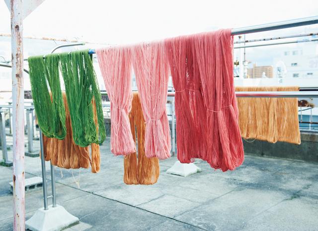 画像: 何度も色を重ねて染め上げた木綿糸は、アトリエの屋上に並べて干す。これは芯の周りに巻く地巻き色。1カセで直径24cmの手まり約20個分になる