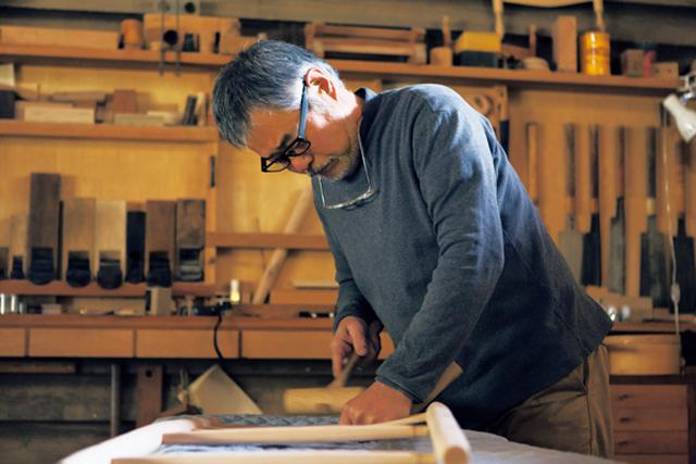 画像: 椅子の後脚に背板をはめ込む作業中の宇納さん