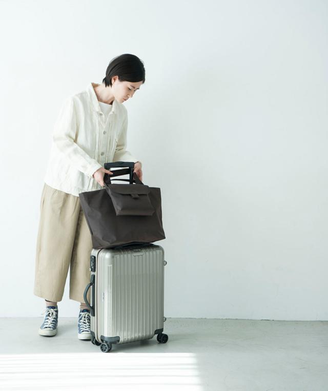 画像: キャリーケースとセットでも単独でも使えるトートを、PVC加工が施された布で。口は安心&安全のファスナーあきにし、背面にはハンドル通しとポケットが。共布で貴重品が入るサブバッグと、旅館への気配りとしてキャスターに装着したいカバーも制作。