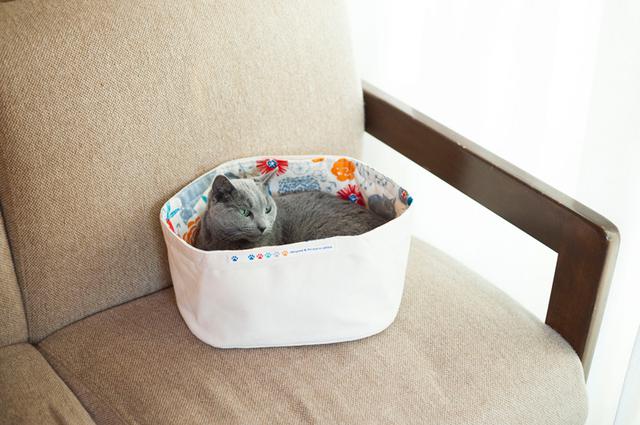 画像: 冒頭の写真で紹介した子どものおもちゃ入れをねこベッドに。ふんわりとした感触で持ち手に手足を引っ掛けにくいから、こんな使い方もおすすめ。表布は適度な張りがあるオックス、裏布はねこモチーフの柄を選んでキュートに。