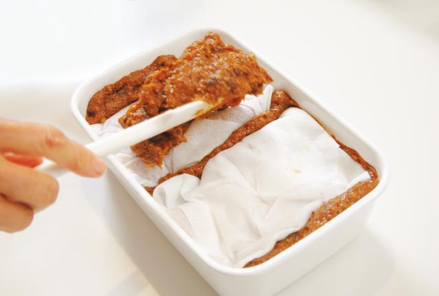 画像: 上部の味噌を1/3くらい取り除き、ペーパータオルに包んだ豚肉をのせ、味噌をかぶせる